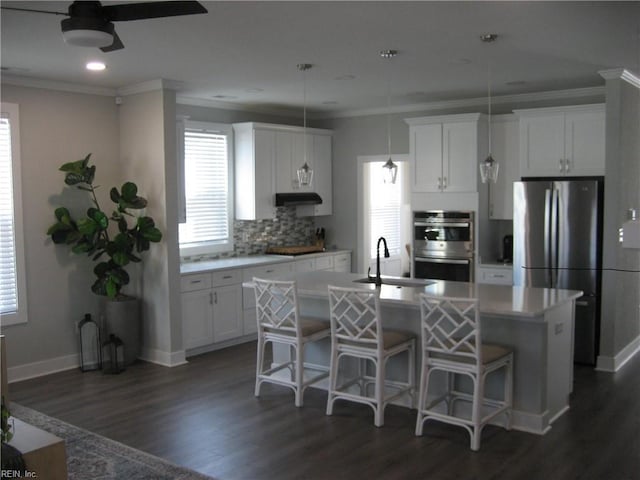 kitchen with stainless steel appliances, white cabinetry, a kitchen island with sink, and sink