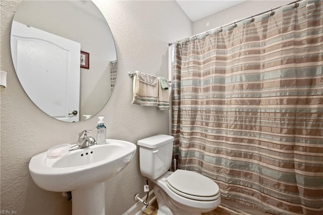 bathroom with toilet, curtained shower, and sink