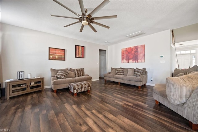 living room featuring ceiling fan, dark hardwood / wood-style floors, and a textured ceiling