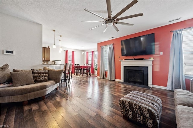 living room with dark hardwood / wood-style flooring, ceiling fan, and a textured ceiling