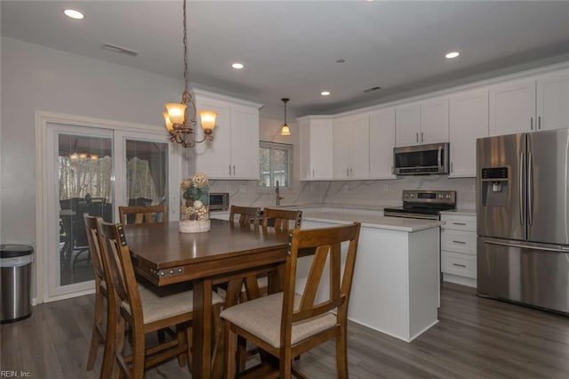 kitchen featuring stainless steel appliances, tasteful backsplash, pendant lighting, white cabinets, and a center island