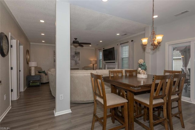 dining space with a textured ceiling, ceiling fan with notable chandelier, ornamental molding, and hardwood / wood-style flooring