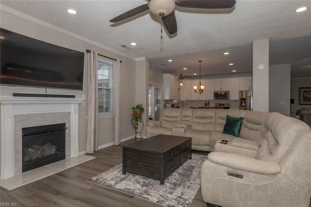 living room with ceiling fan with notable chandelier, a textured ceiling, a high end fireplace, dark hardwood / wood-style floors, and crown molding