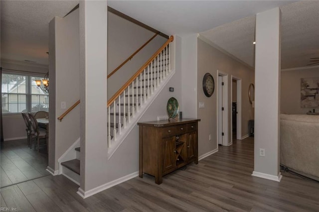 staircase with hardwood / wood-style flooring, a textured ceiling, and a notable chandelier