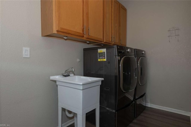 laundry room with cabinets, separate washer and dryer, sink, and dark wood-type flooring