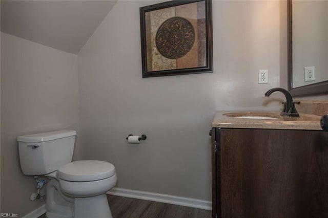 bathroom featuring vaulted ceiling, toilet, hardwood / wood-style flooring, and vanity