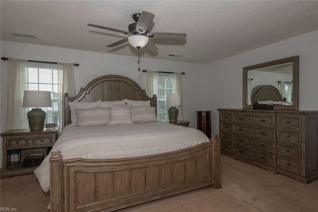 bedroom featuring light carpet, ceiling fan, and a textured ceiling