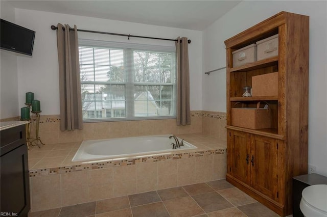 bathroom with a relaxing tiled tub, toilet, and vanity