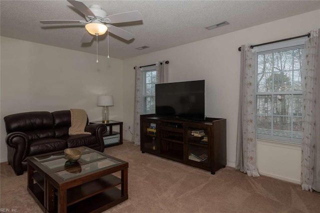 carpeted living room featuring ceiling fan, plenty of natural light, and a textured ceiling