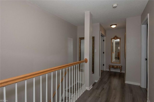 hallway with a textured ceiling and dark hardwood / wood-style flooring