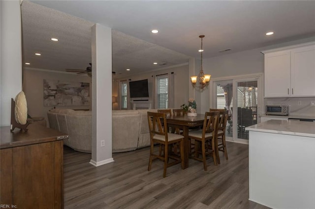 dining area with ceiling fan with notable chandelier, dark hardwood / wood-style floors, and ornamental molding