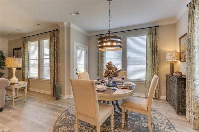 dining space featuring light hardwood / wood-style flooring, crown molding, and an inviting chandelier