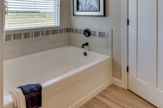 bathroom with a tub to relax in and hardwood / wood-style floors