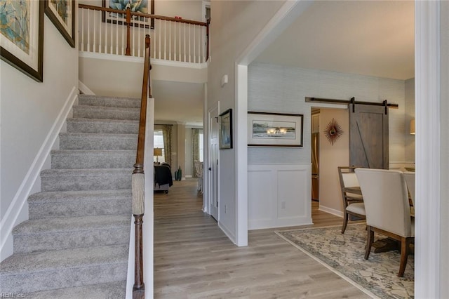 entryway featuring a towering ceiling, light hardwood / wood-style flooring, and a barn door