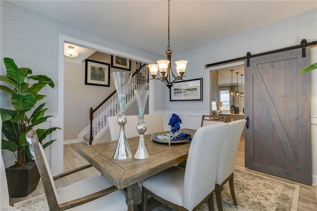 dining room with a barn door, light hardwood / wood-style flooring, and a notable chandelier