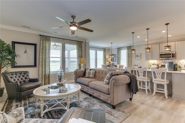 living room with ceiling fan, crown molding, and light hardwood / wood-style flooring