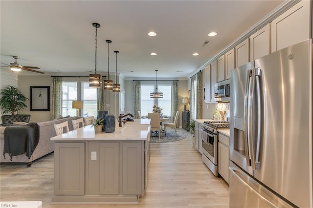 kitchen with hanging light fixtures, a kitchen island with sink, gray cabinetry, and stainless steel appliances