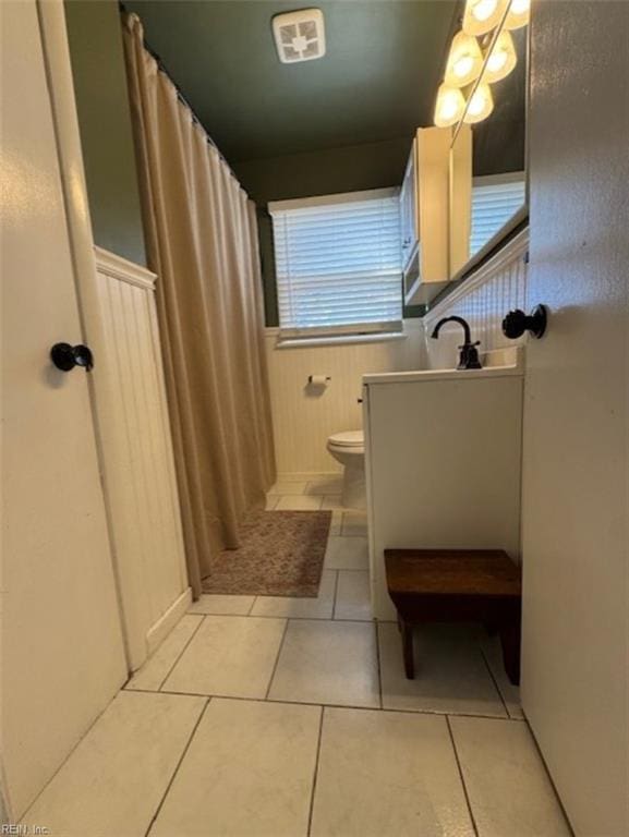 bathroom with toilet, vanity, and tile patterned flooring