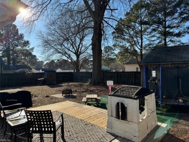 wooden terrace featuring an outdoor fire pit and a storage unit