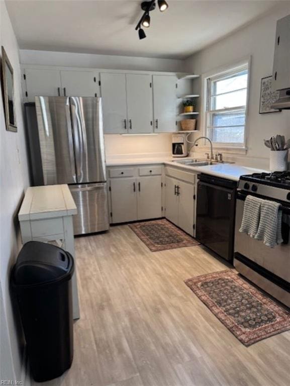 kitchen with white cabinetry, light hardwood / wood-style floors, ventilation hood, stainless steel appliances, and sink