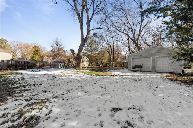 yard layered in snow featuring a garage and an outdoor structure