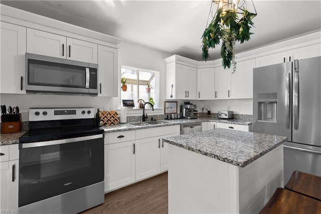 kitchen featuring a kitchen island, sink, white cabinetry, light stone countertops, and stainless steel appliances