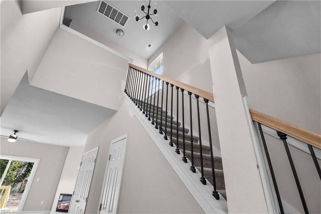 stairs with ceiling fan with notable chandelier