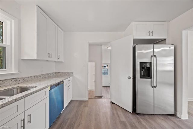 kitchen featuring appliances with stainless steel finishes, light hardwood / wood-style flooring, white cabinetry, and light stone countertops