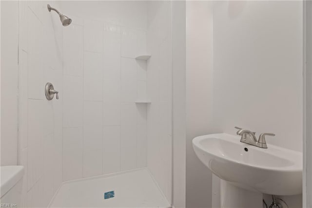 bathroom with sink, toilet, and a tile shower