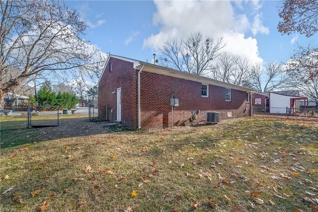 rear view of property with central air condition unit and a yard