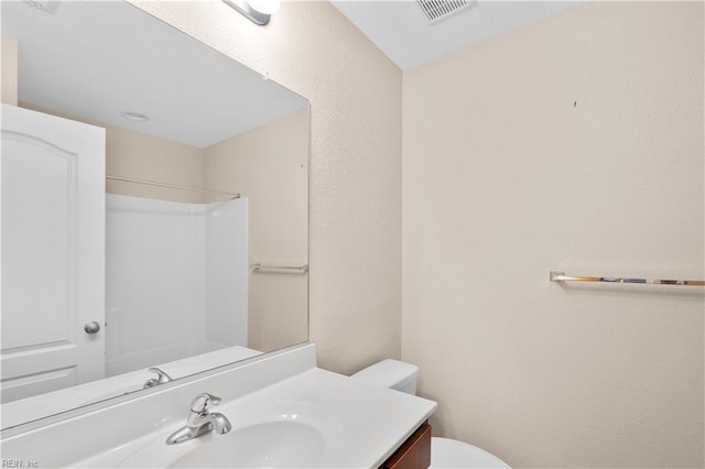 bathroom with toilet, vanity, and walk in shower