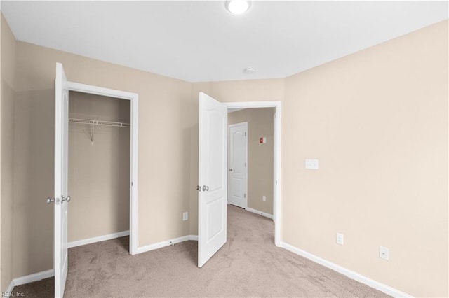 unfurnished bedroom featuring a closet and light colored carpet