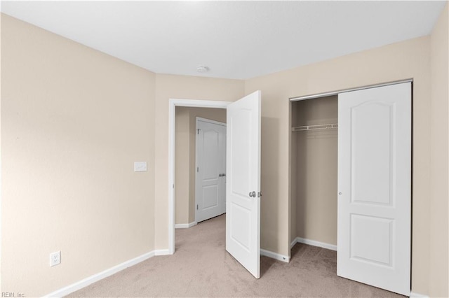 unfurnished bedroom with light colored carpet and a closet