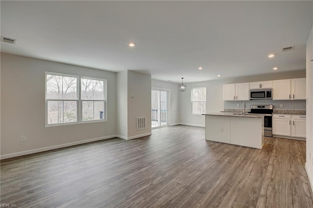 kitchen with white cabinetry, appliances with stainless steel finishes, a center island with sink, and a healthy amount of sunlight