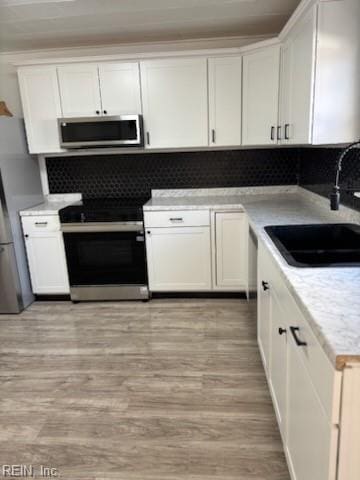 kitchen with light hardwood / wood-style floors, sink, white cabinetry, and stainless steel appliances