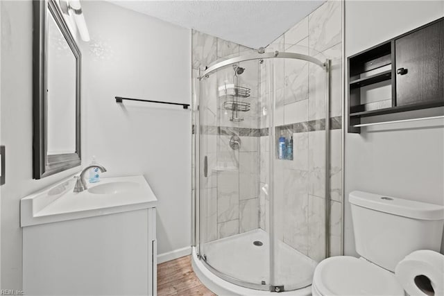 bathroom featuring a shower with shower door, vanity, wood-type flooring, and toilet