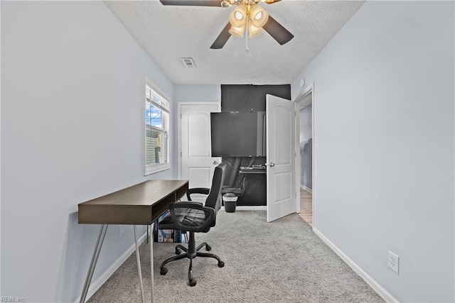 carpeted office space featuring a textured ceiling and ceiling fan