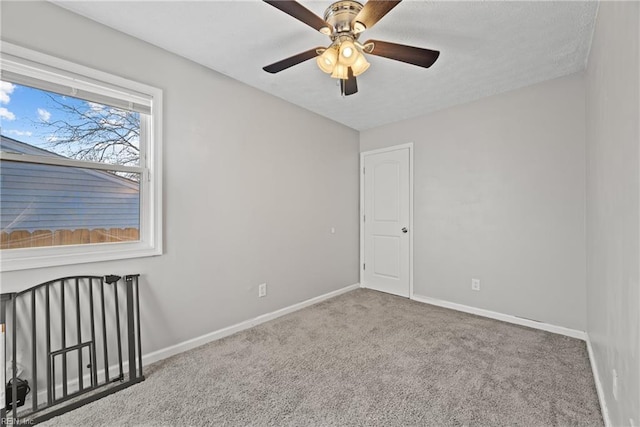 carpeted spare room with ceiling fan