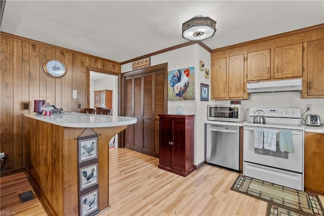 kitchen featuring appliances with stainless steel finishes, wooden walls, ornamental molding, kitchen peninsula, and light wood-type flooring