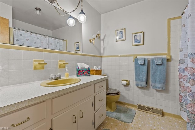 bathroom with toilet, tile patterned flooring, tile walls, vanity, and curtained shower