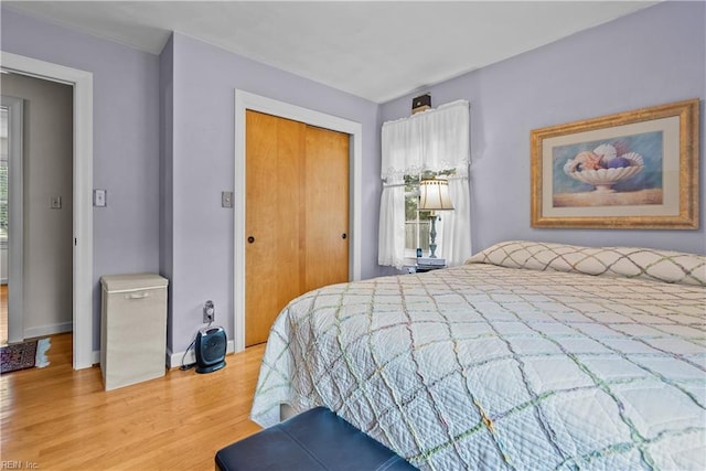 bedroom with light wood-type flooring, a closet, and multiple windows