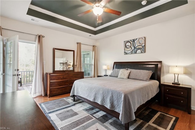 bedroom featuring ceiling fan, ornamental molding, hardwood / wood-style floors, and a tray ceiling