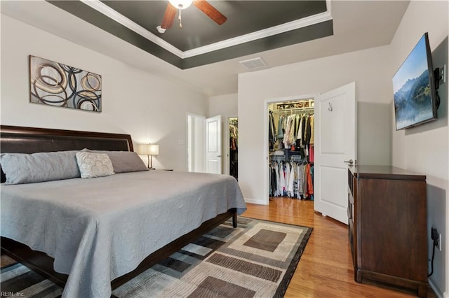 bedroom with ceiling fan, a closet, a walk in closet, and a raised ceiling