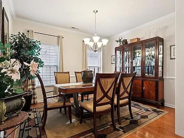 dining area featuring ornamental molding, a healthy amount of sunlight, hardwood / wood-style flooring, and a notable chandelier