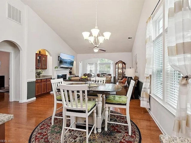 dining area featuring high vaulted ceiling, dark hardwood / wood-style flooring, and ceiling fan with notable chandelier