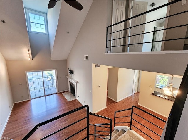 stairway featuring ceiling fan, hardwood / wood-style floors, a healthy amount of sunlight, and a high ceiling