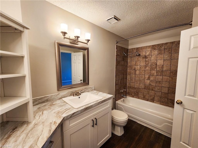 full bathroom featuring toilet, hardwood / wood-style floors, tiled shower / bath, a textured ceiling, and vanity