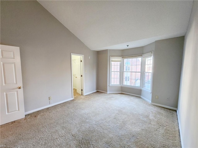 unfurnished room featuring lofted ceiling and light colored carpet