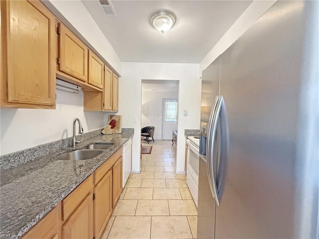 kitchen featuring dark stone countertops, sink, white dishwasher, stainless steel fridge with ice dispenser, and light tile patterned floors