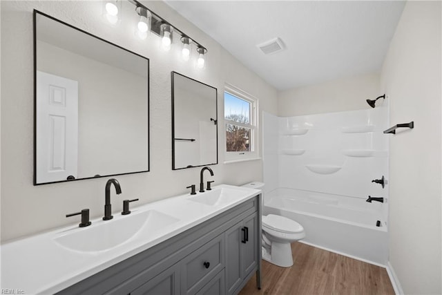 full bathroom with wood-type flooring, toilet, vanity, and shower / washtub combination